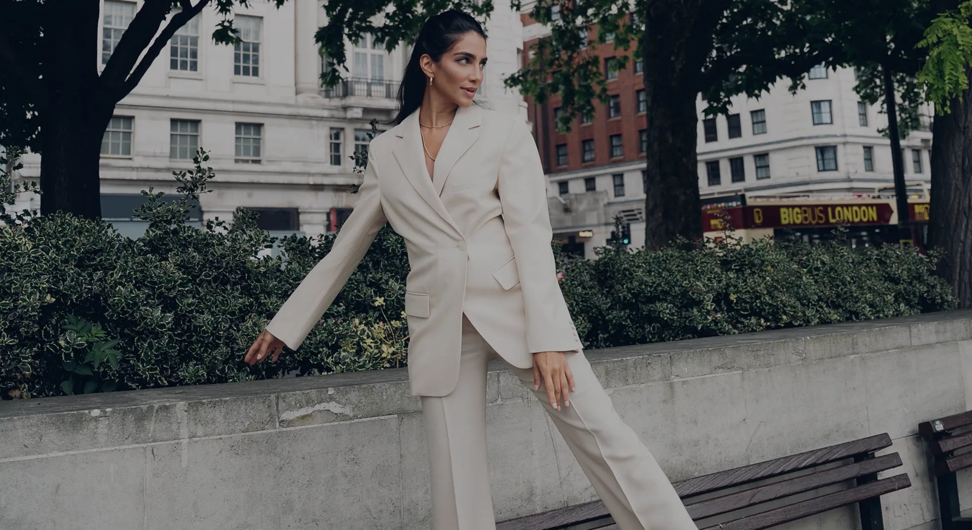 Woman wearing a chic beige suit posing stylishly outdoors in an urban city setting